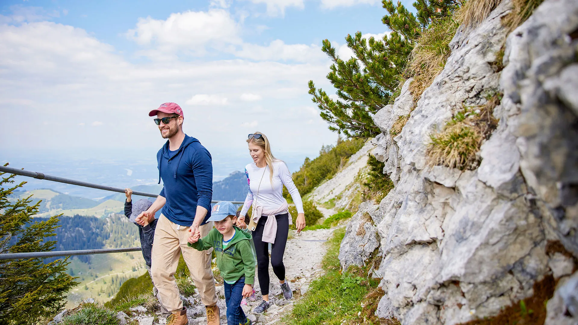 Familie mit Kindern wandert auf felsigem Bergpfad mit Weitblick