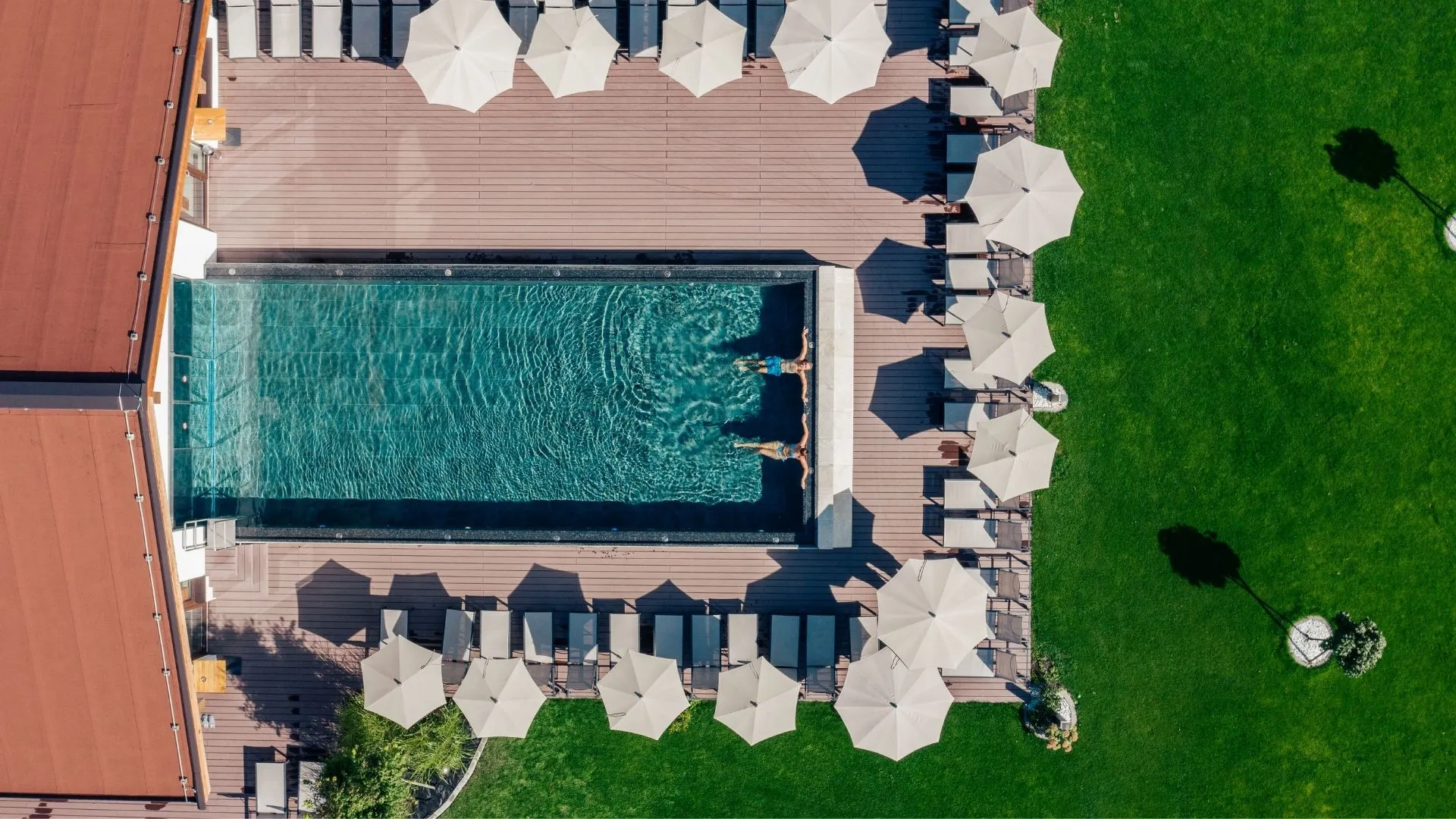 Luftaufnahme eines Pools mit Sonnenschirmen und Liegen auf der Terrasse eines Hotels