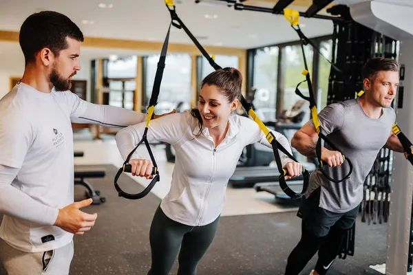 Trainer betreut Gäste beim TRX-Training im Fitnessraum