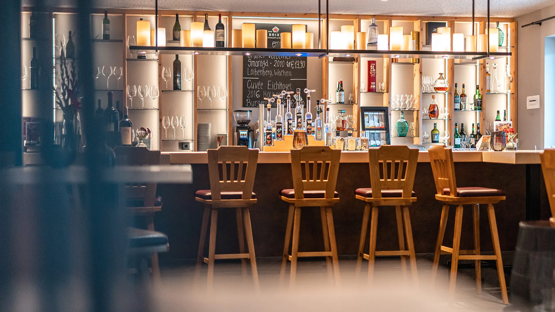 Hotelbar mit Holzbarhockern und beleuchtetem Flaschenregal