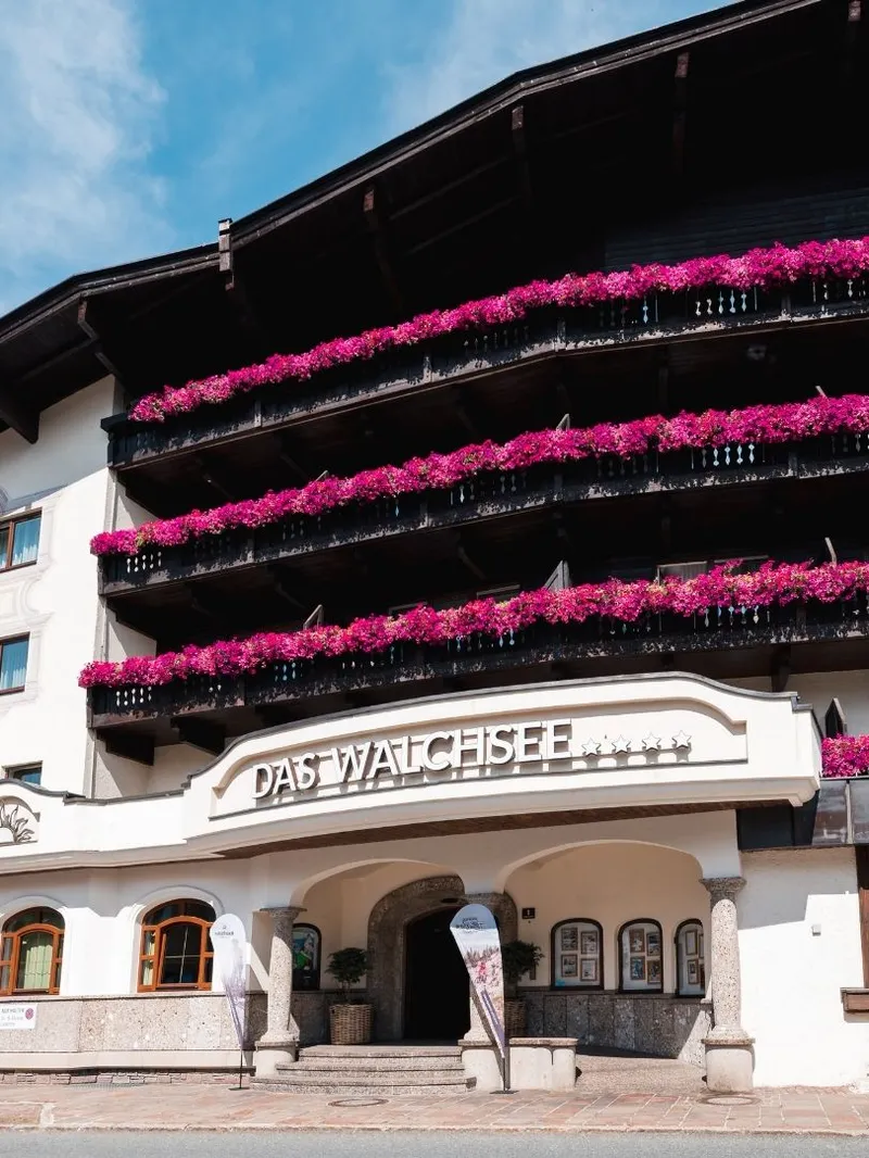 Hotel Das Walchsee mit pinken Blumenbalkonen und Eingangsbereich
