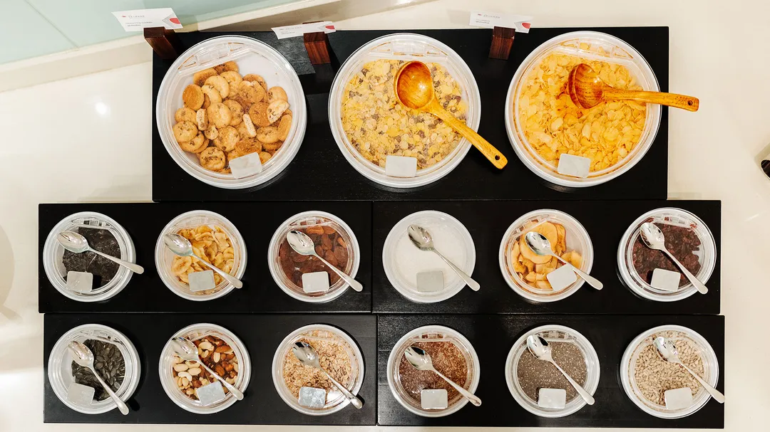 Müsli-Buffet mit verschiedenen Cerealien, Nüssen und Trockenfrüchten in Schälchen