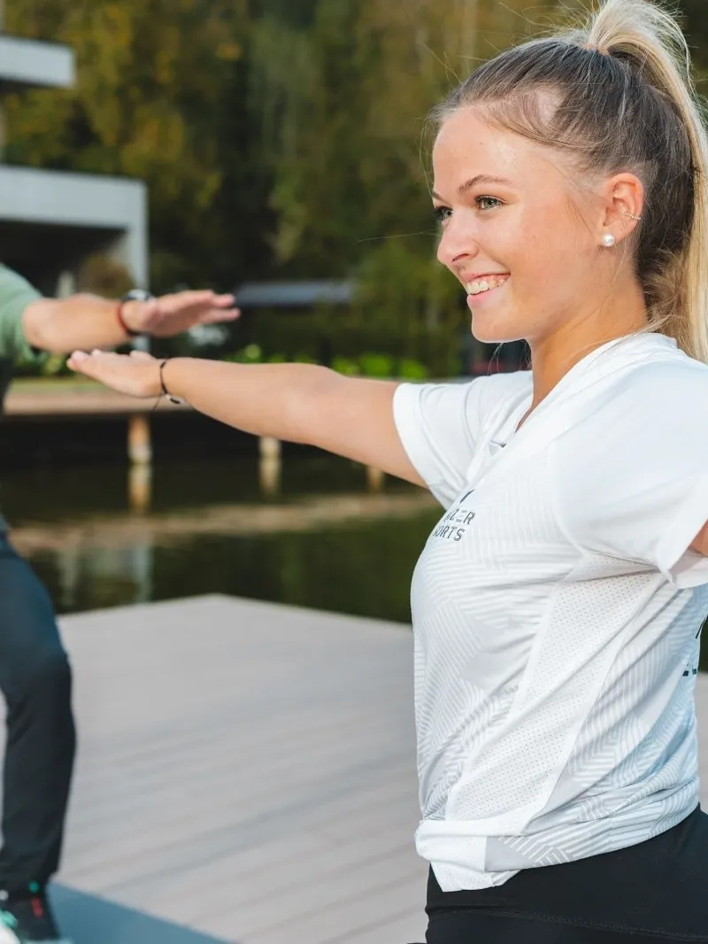 Frau und Mann machen Yoga auf einem Steg am See