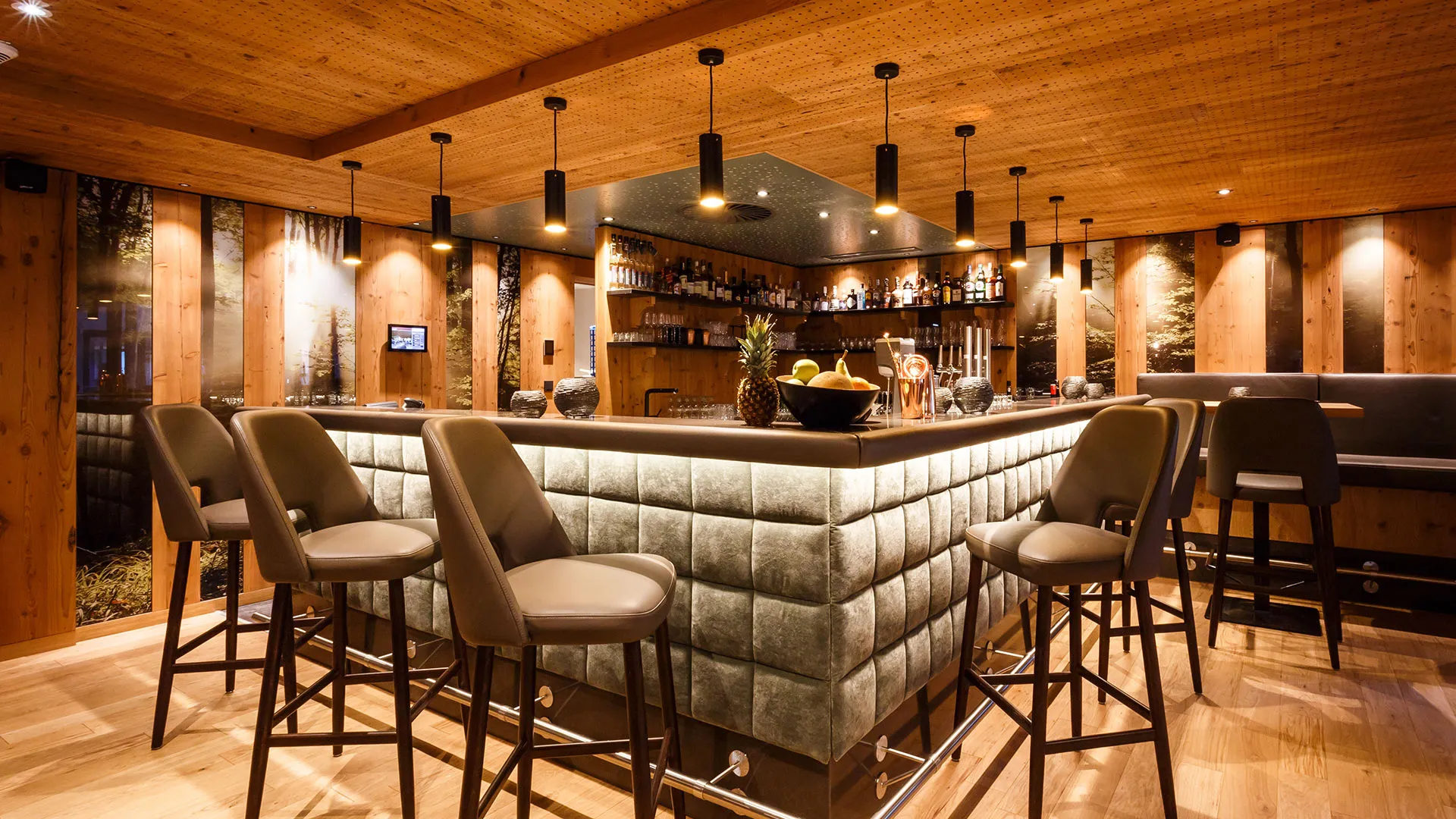 Hotelbar mit Barhockern, Holzverkleidung und beleuchteter Flaschenwand