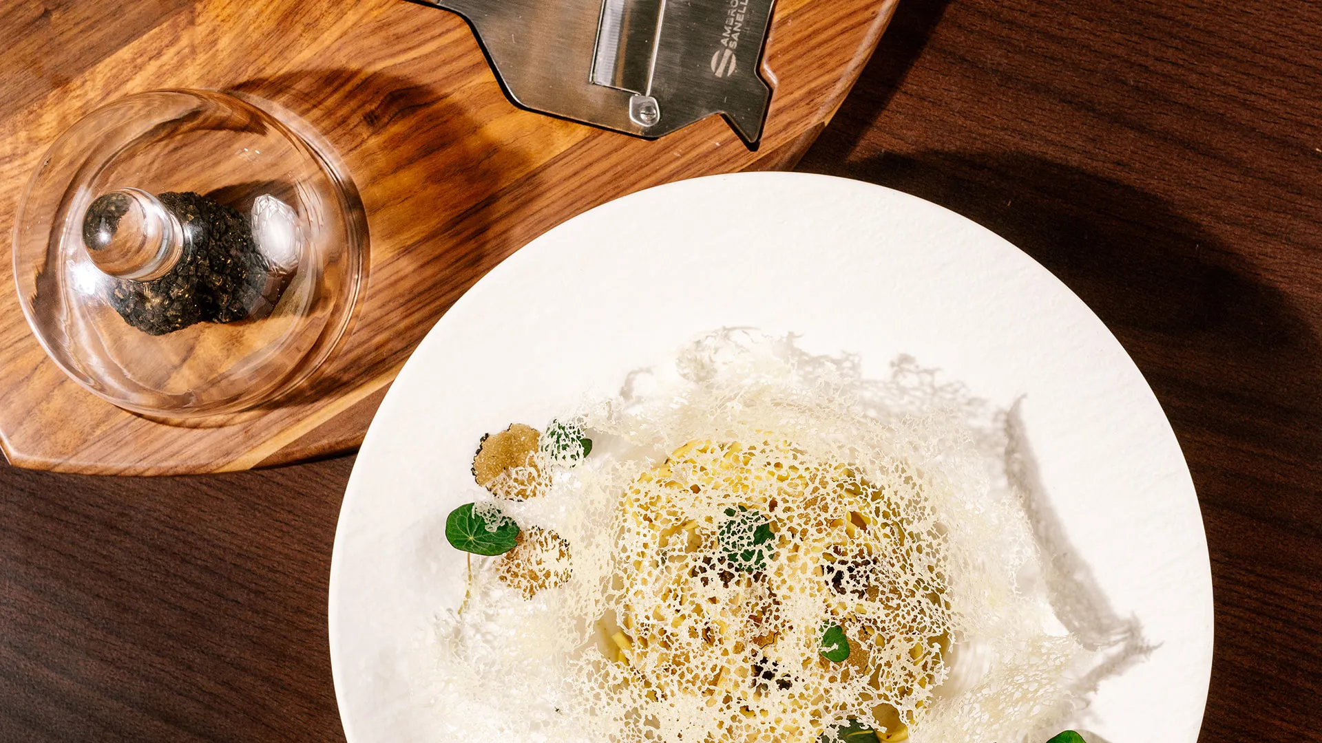 Fine-Dining-Gericht mit Kräutergitter und Trüffel auf weißem Teller