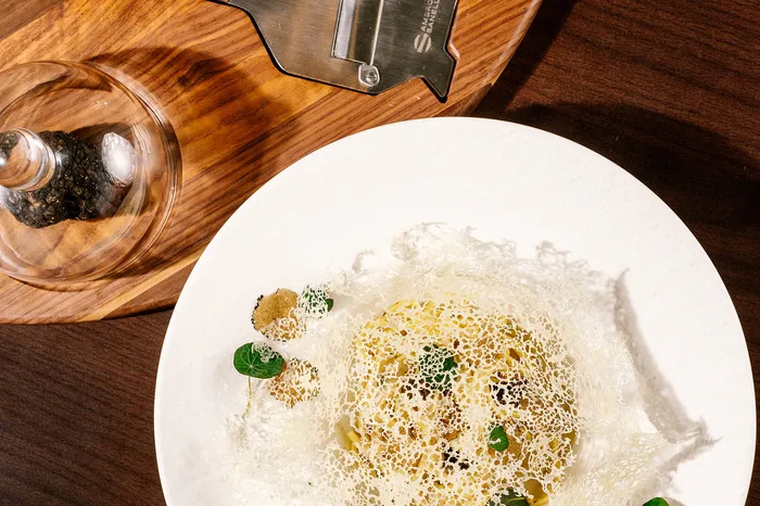 Fine-Dining-Gericht mit Kräutergitter und Trüffel auf weißem Teller