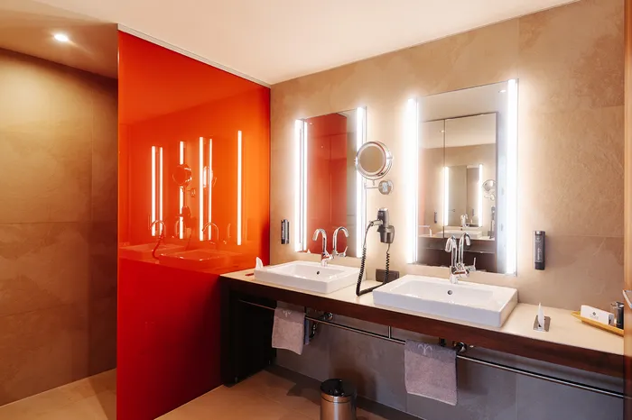 Modernes Badezimmer mit zwei Waschbecken und beleuchteten Spiegeln