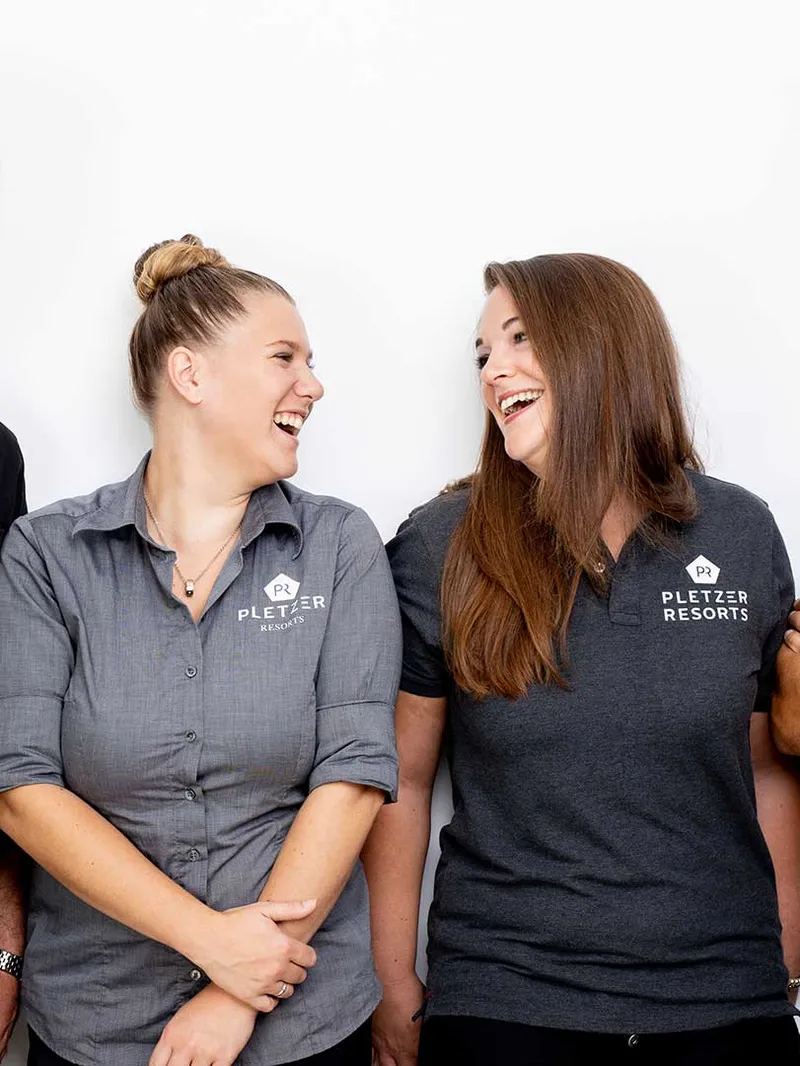 Vier lachende Mitarbeiter der Pletzer Resorts in Uniform