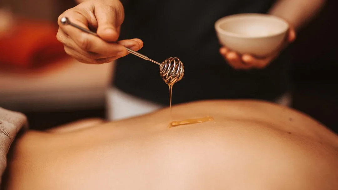 Honig wird für eine Massage auf den Rücken geträufelt