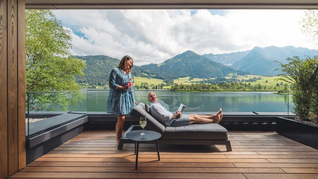 Paar entspannt auf Terrasse mit Blick auf See und Berge