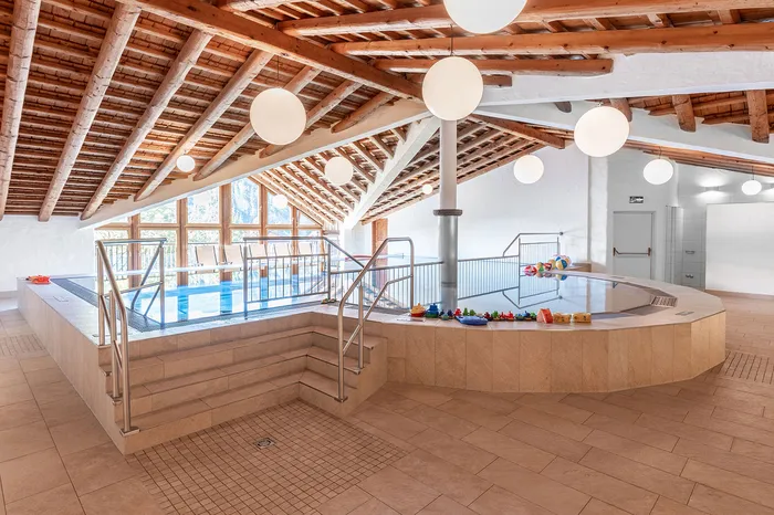 Kinderbecken mit Spielzeug im Hallenbad unter Holzdachstuhl