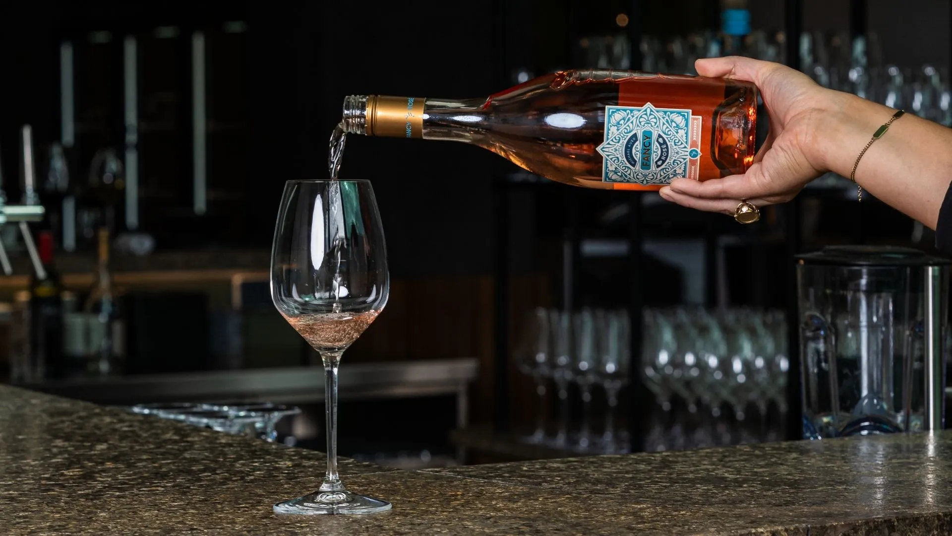 Rosé Wein wird an der Bar in ein Glas eingeschenkt