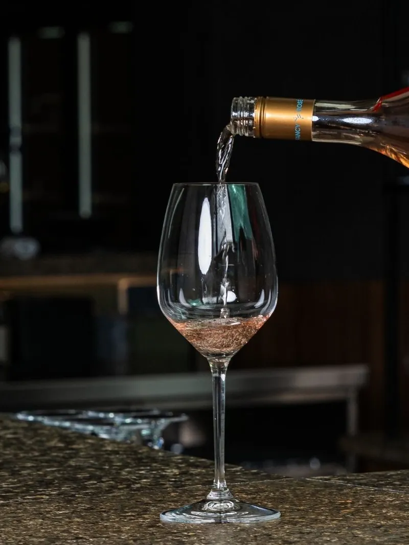 Rosé Wein wird an der Bar in ein Glas eingeschenkt