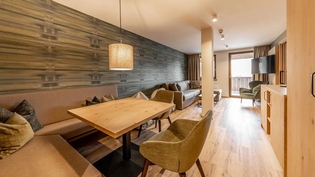 Wohnbereich mit Esstisch, Sitzbank und Lounge mit Balkonzugang