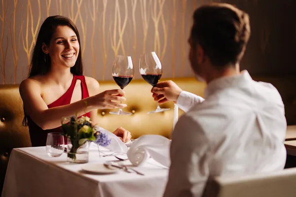 Paar stößt mit Rotwein an einem festlich gedeckten Restauranttisch an