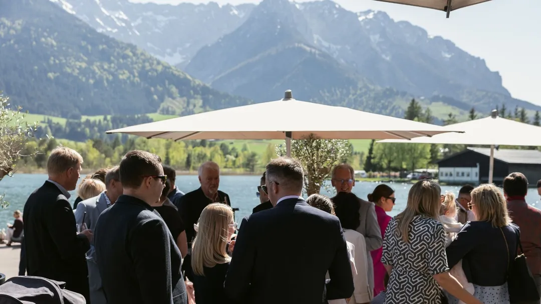 Gäste bei Feier auf Terrasse am See mit Bergpanorama