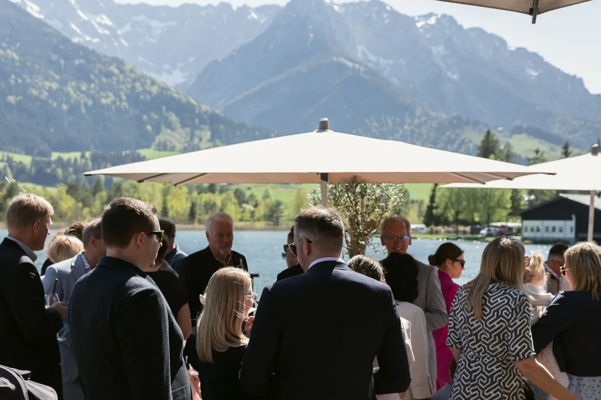 Gäste bei Feier auf Terrasse am See mit Bergpanorama