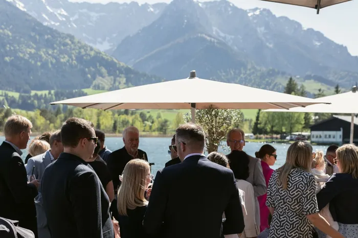 Gäste bei Feier auf Terrasse am See mit Bergpanorama