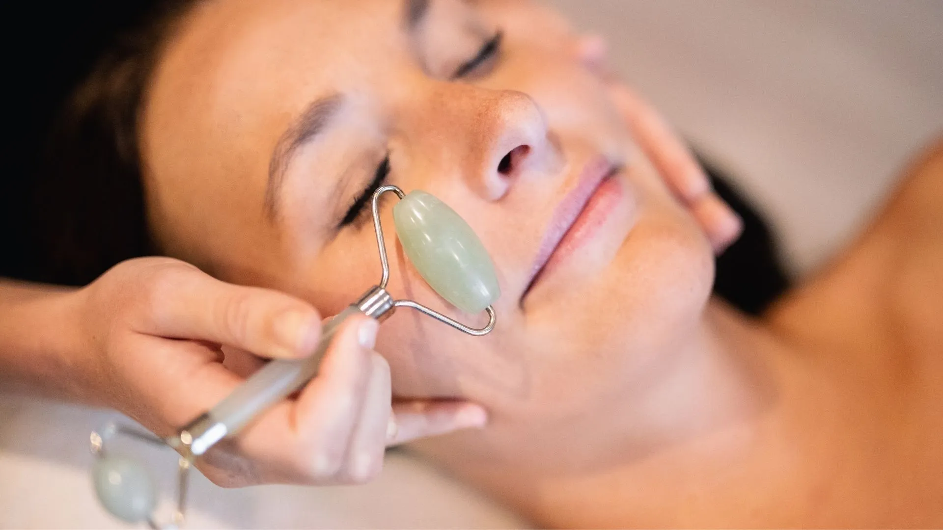 Frau erhält Gesichtsmassage mit Jade-Roller im Spa
