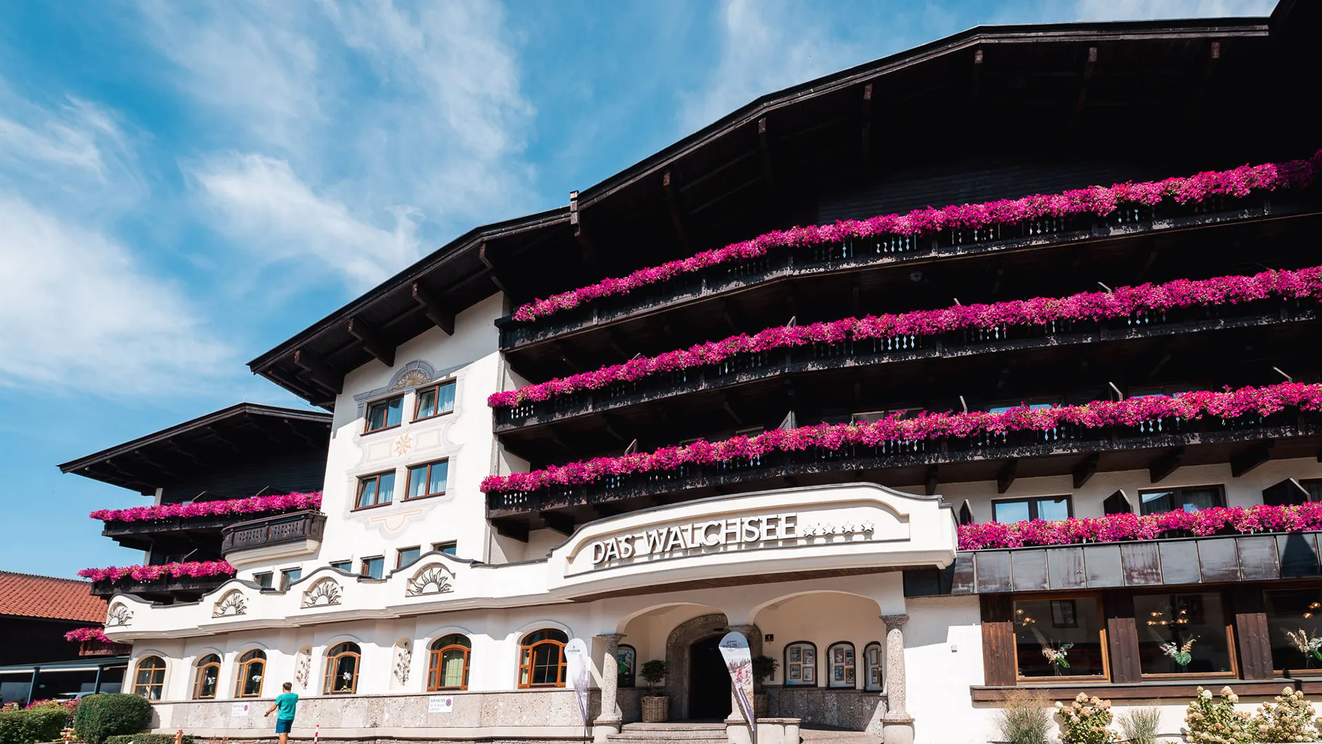 Hotel Das Walchsee mit Balkonen voller pinker Blumen
