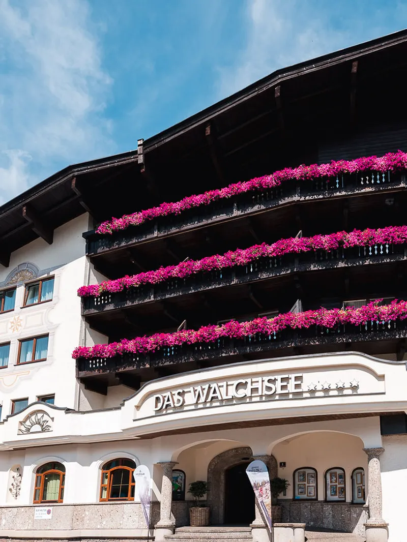 Hotel Das Walchsee mit Balkonen voller pinker Blumen
