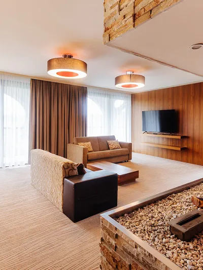 Wohnbereich einer Suite mit Sofas, TV und Kieselstein-Feuerstelle