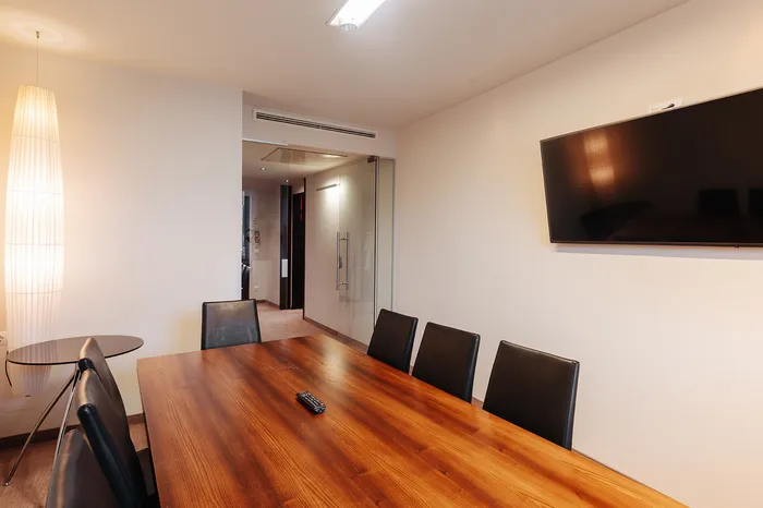 Kleiner Besprechungsraum mit Holztisch, Lederstühlen und Wandbildschirm