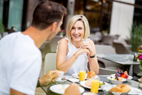 Paar beim Frühstück auf der Terrasse mit Obst, Croissant und Orangensaft