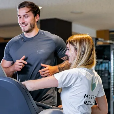 Fitnesstrainerin erklärt Mann Laufband im Fitnessraum
