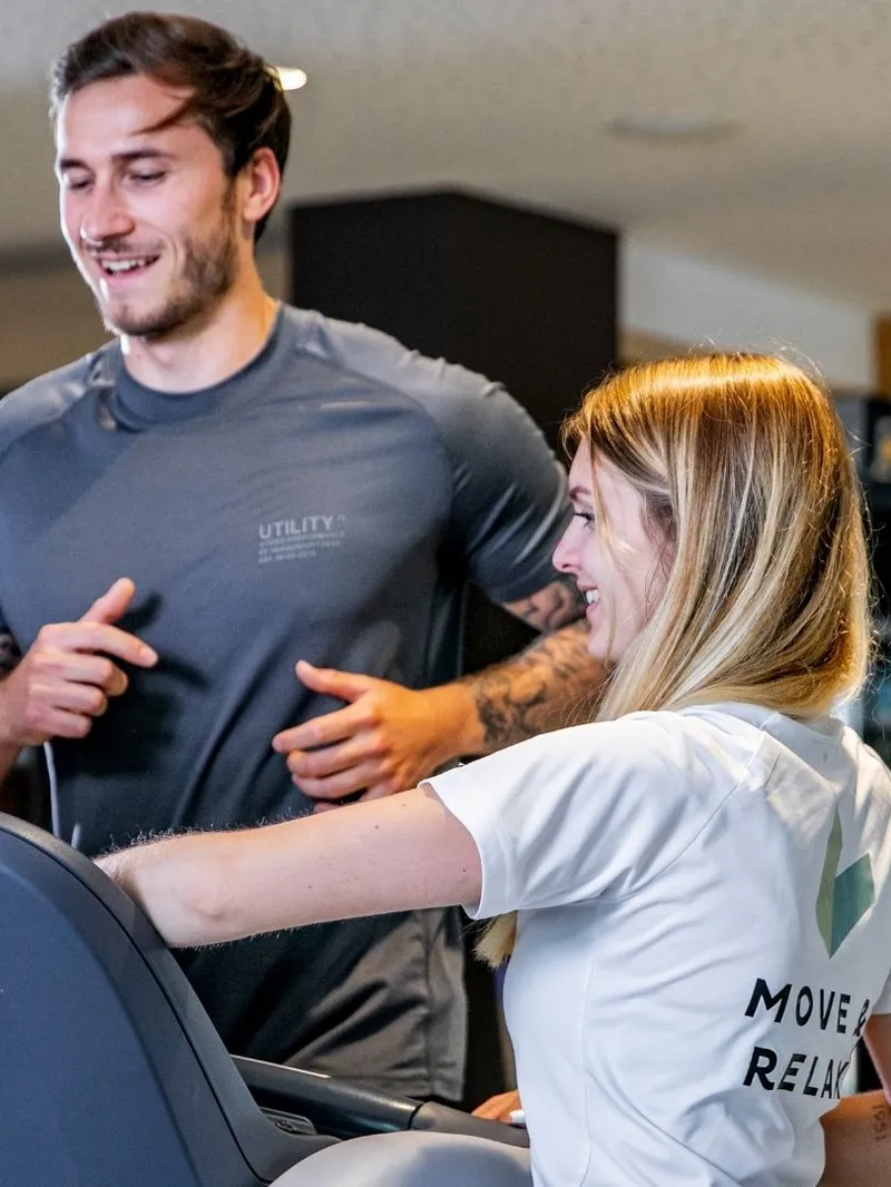 Fitnesstrainerin erklärt Mann Laufband im Fitnessraum
