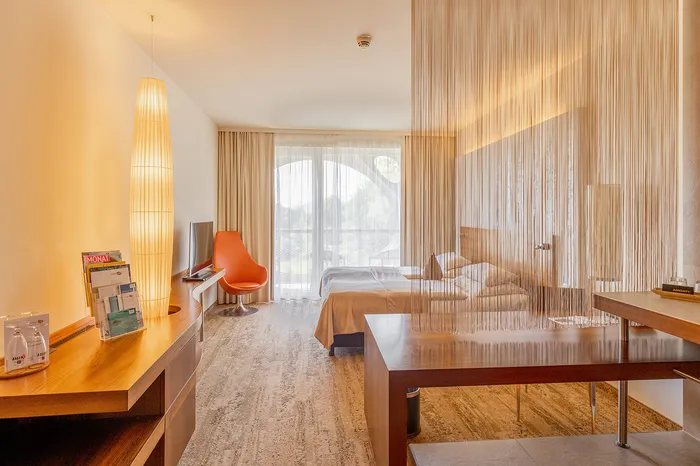 Hotelzimmer mit Doppelbett, Sitzecke und Fadenvorhang als Raumteiler