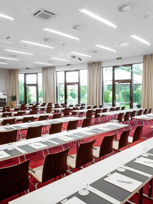 Großer Seminarraum mit Tischreihen, Stühlen und Leinwand