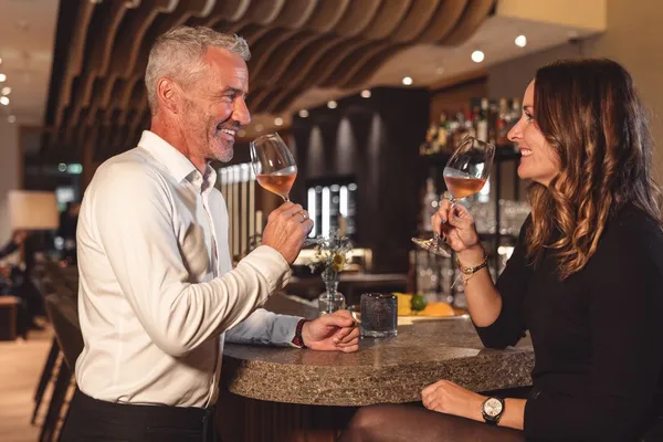 Paar stößt mit Weingläsern an der Hotelbar an