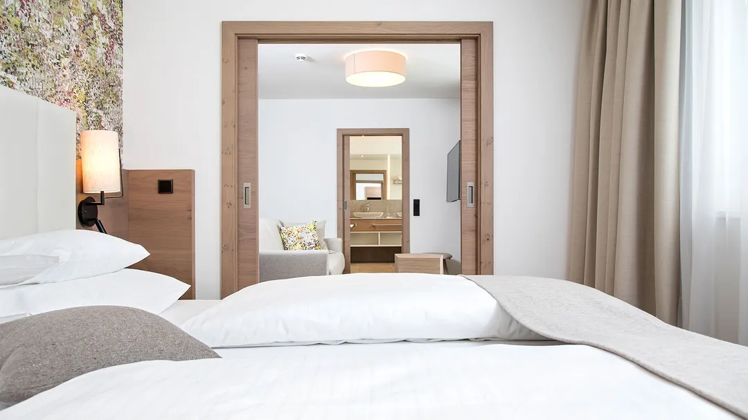 Suite mit Doppelbett, Blick durch Schiebetür in Wohnbereich und Bad