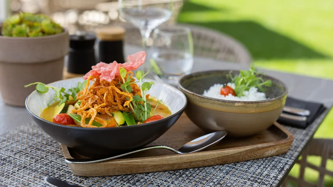 Currygericht mit Gemüse und Reis auf einem Tisch im Freien