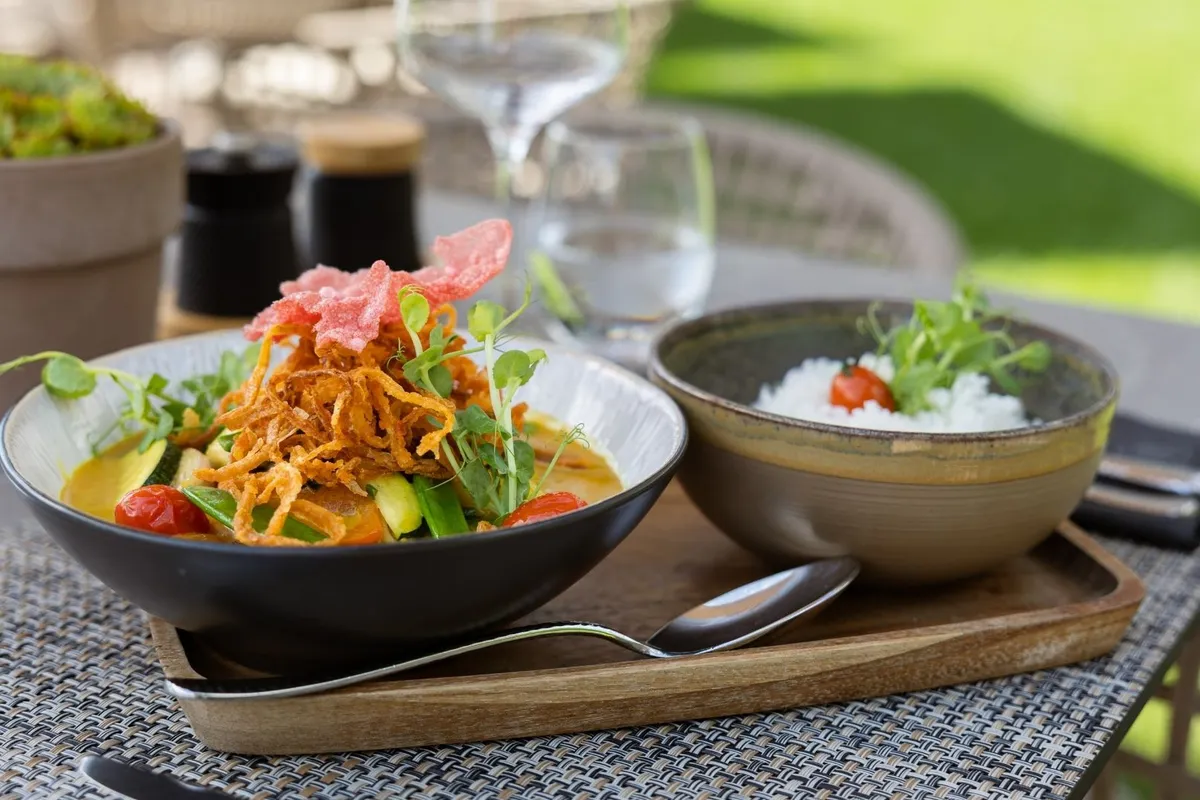 Currygericht mit Gemüse und Reis auf einem Tisch im Freien