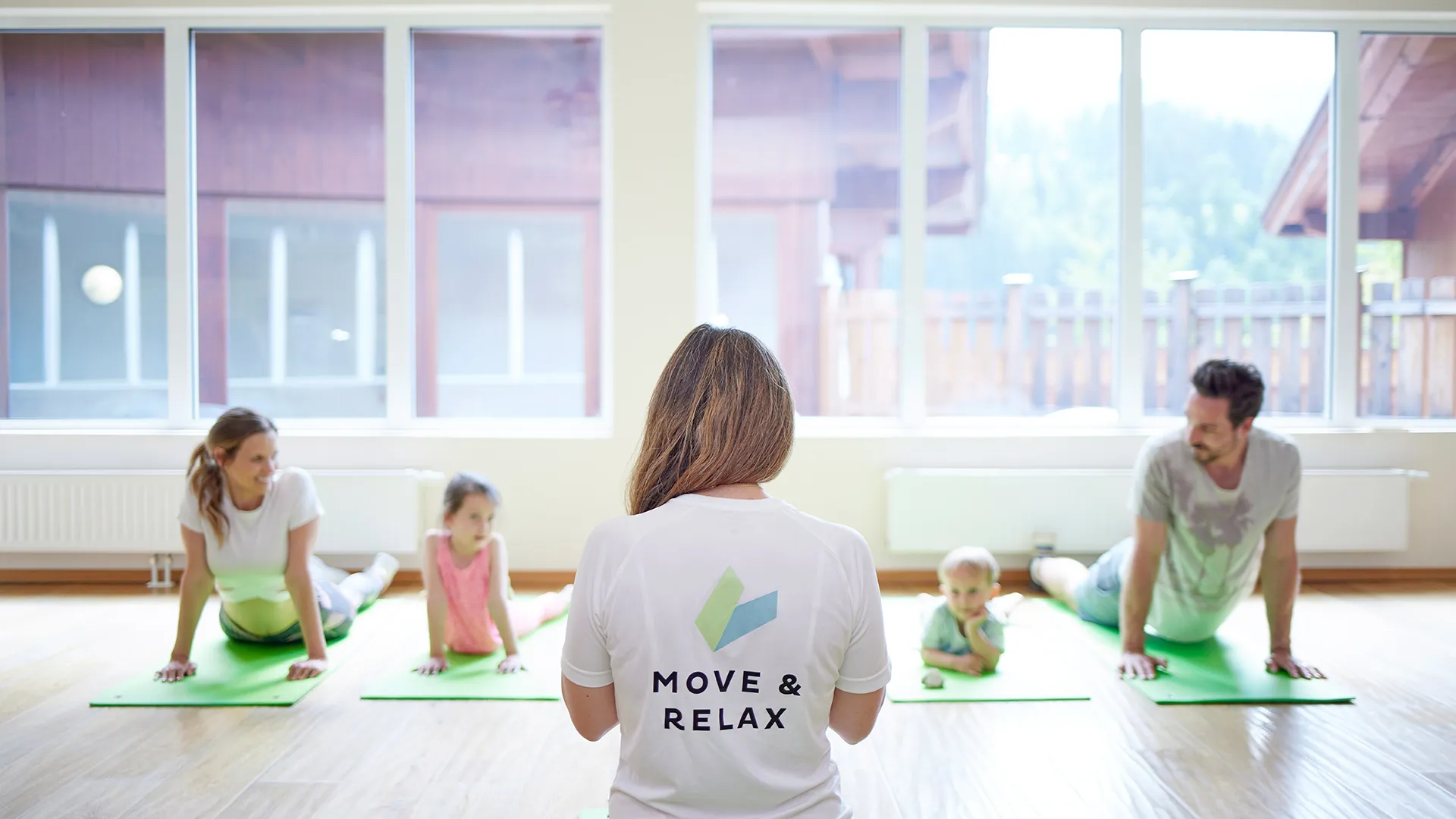 Familie macht Yoga-Übungen auf Matten mit Trainerin im Kursraum