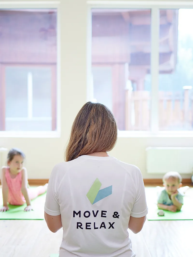 Familie macht Yoga-Übungen auf Matten mit Trainerin im Kursraum
