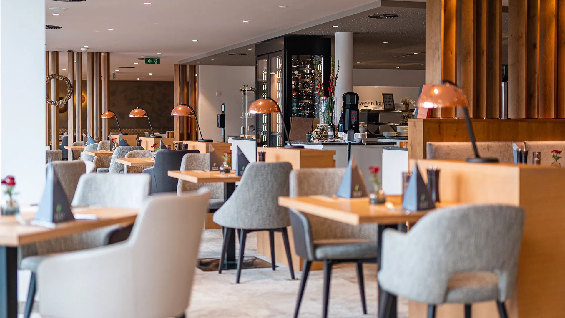 Restaurant mit gedeckten Tischen, Sesseln und Kupferlampen im Hotel Das Hohe Salve
