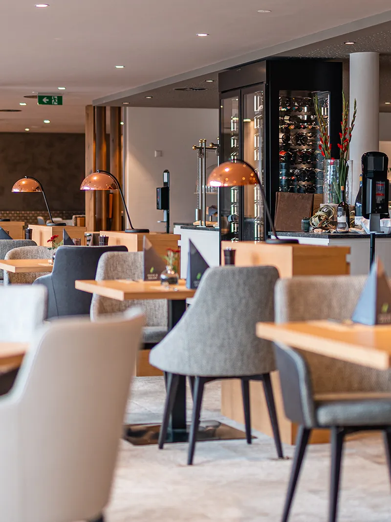 Restaurant mit gedeckten Tischen, Sesseln und Kupferlampen im Hotel Das Hohe Salve
