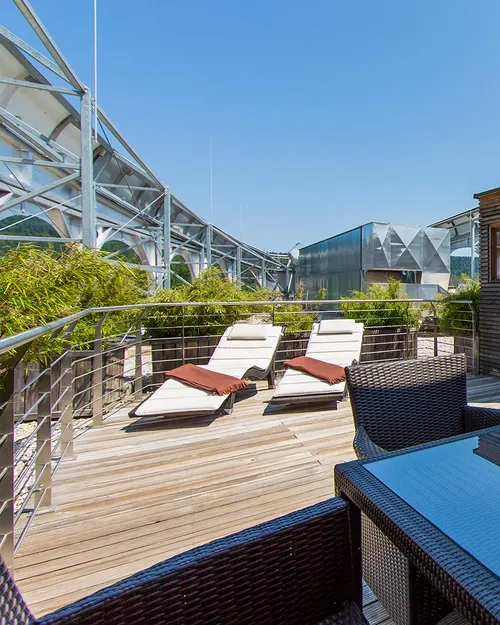 Dachterrasse mit Loungemöbeln, Sonnenliegen und kleiner Holzsauna