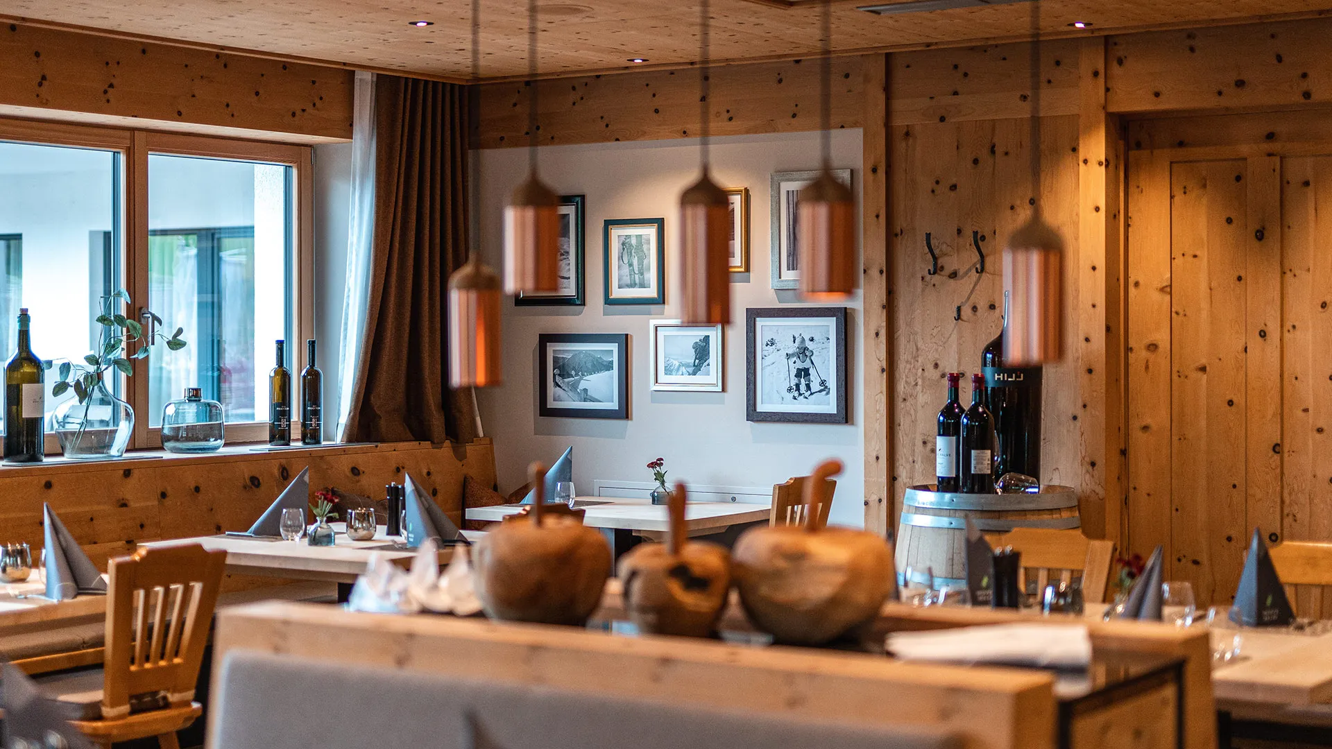 Rustikales Restaurant mit Holzvertäfelung, gedeckten Tischen und Bildern an der Wand