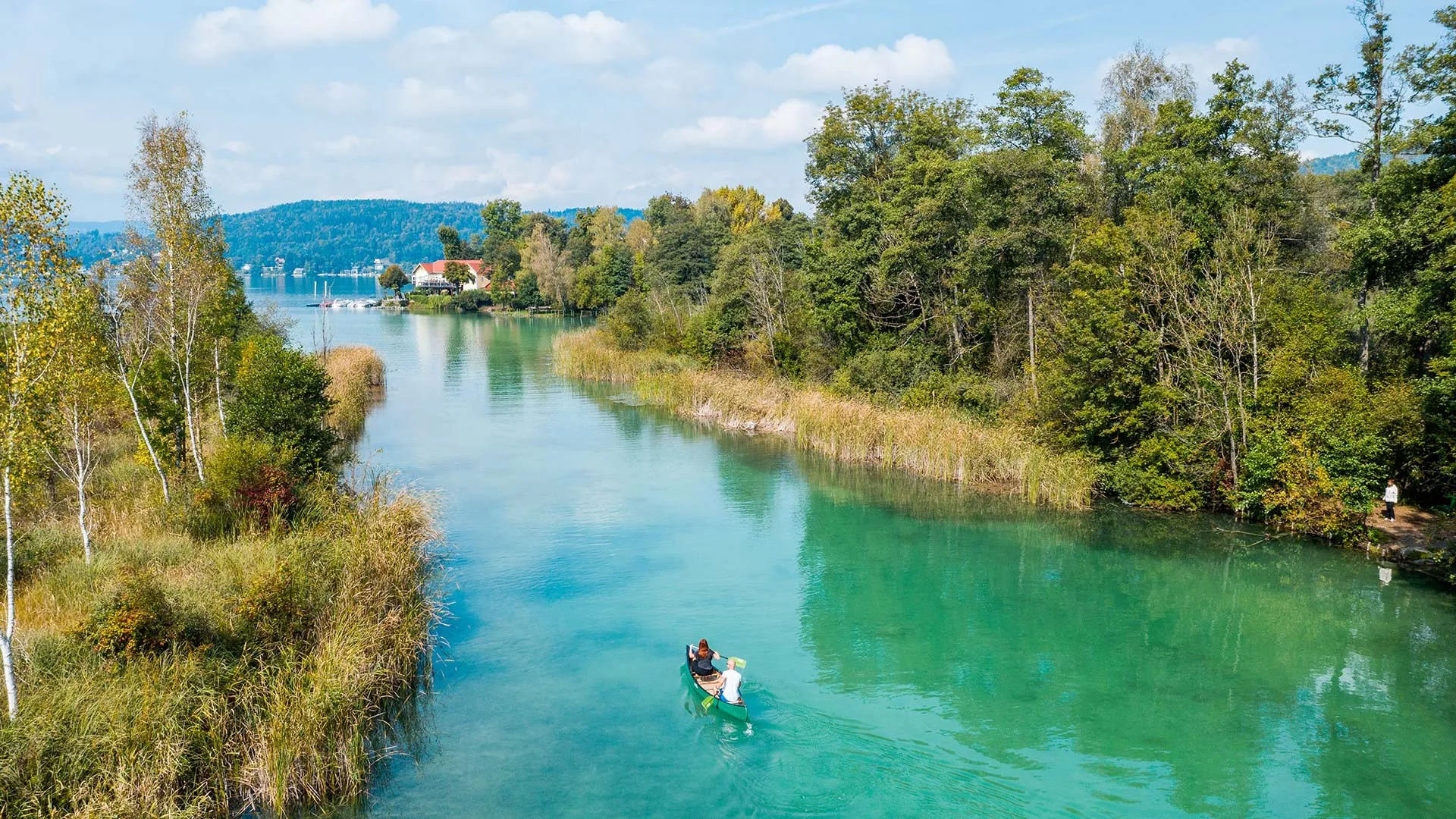 Kanufahrer auf türkisfarbenem Fluss zwischen Bäumen und Schilf