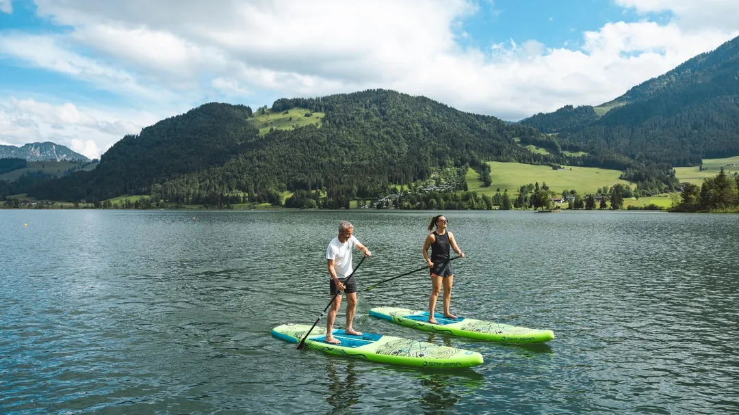 Zwei Personen beim Stand-Up-Paddling auf einem Bergsee