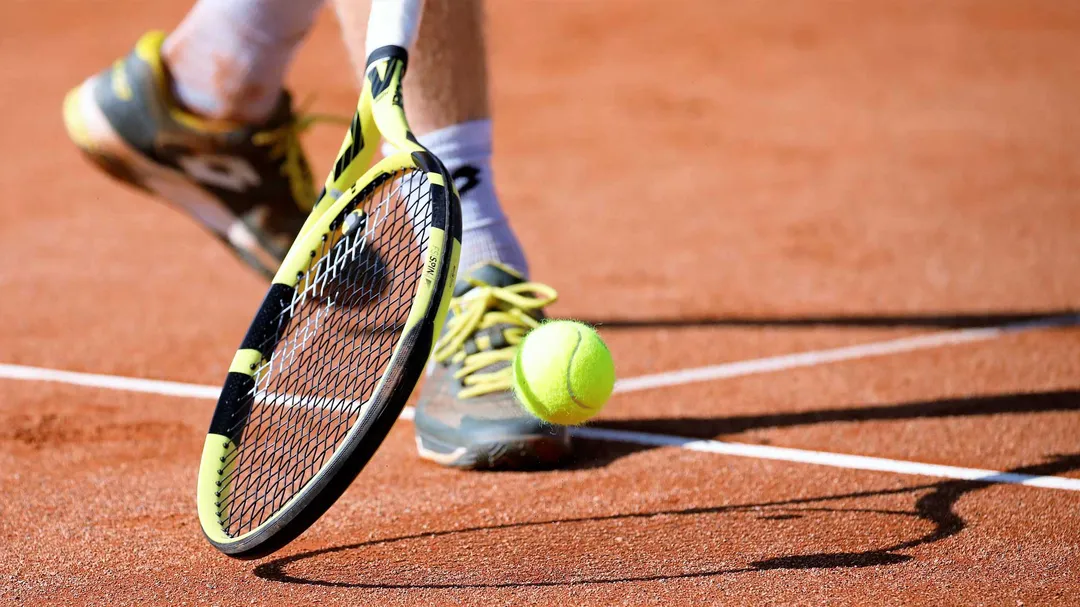 Tennisschläger und Ball auf einem Sandplatz