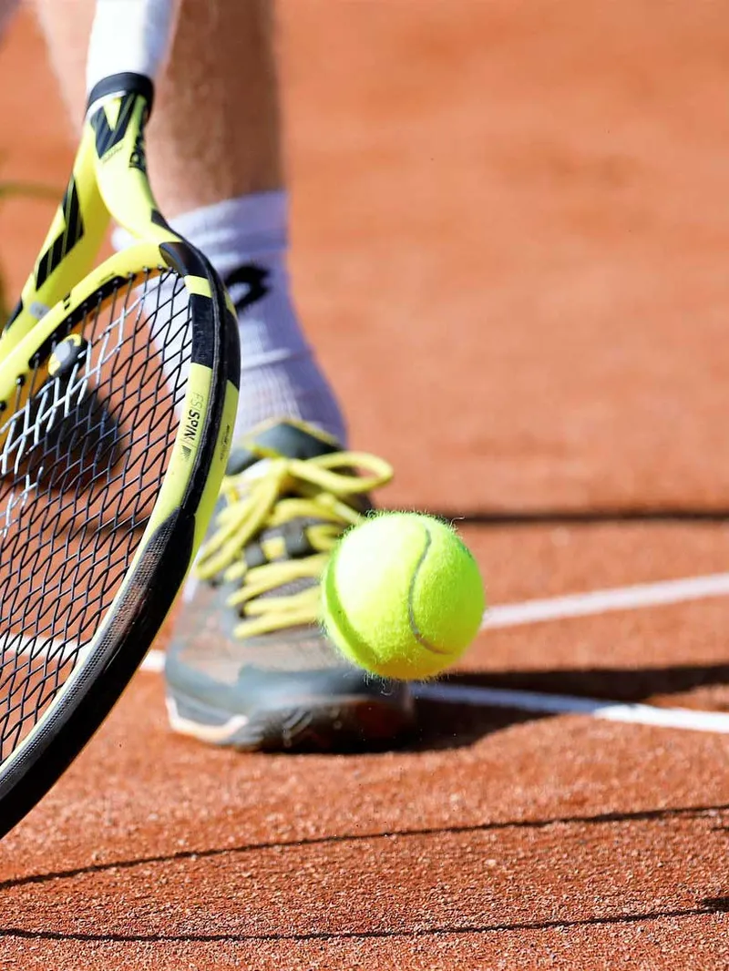 Tennisschläger und Ball auf einem Sandplatz