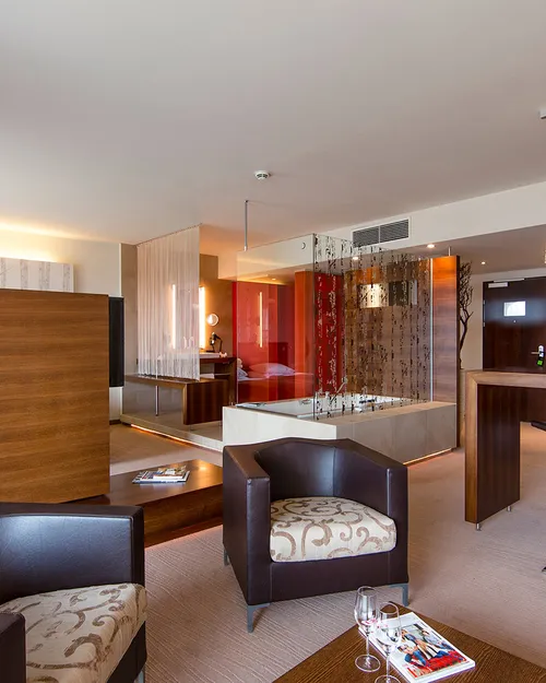 Suite mit Wohnbereich, Sitzecke, Bar und Bett mit Birkenstämmen als Dekoration