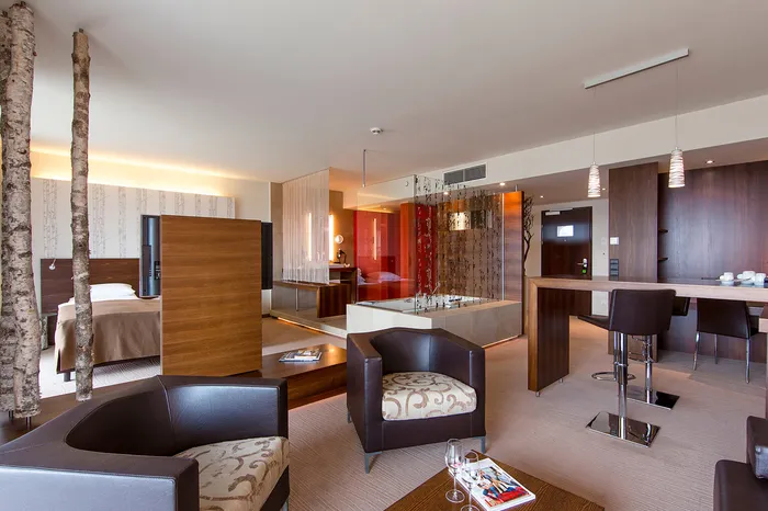 Suite mit Wohnbereich, Sitzecke, Bar und Bett mit Birkenstämmen als Dekoration