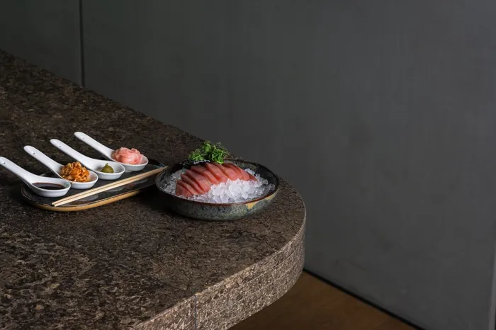 Thunfisch-Sashimi auf Eis mit Beilagen und Sojasauce auf Steintisch