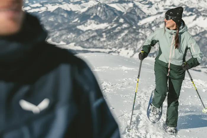 Schneeschuhwanderin mit Stöcken vor winterlichem Bergpanorama